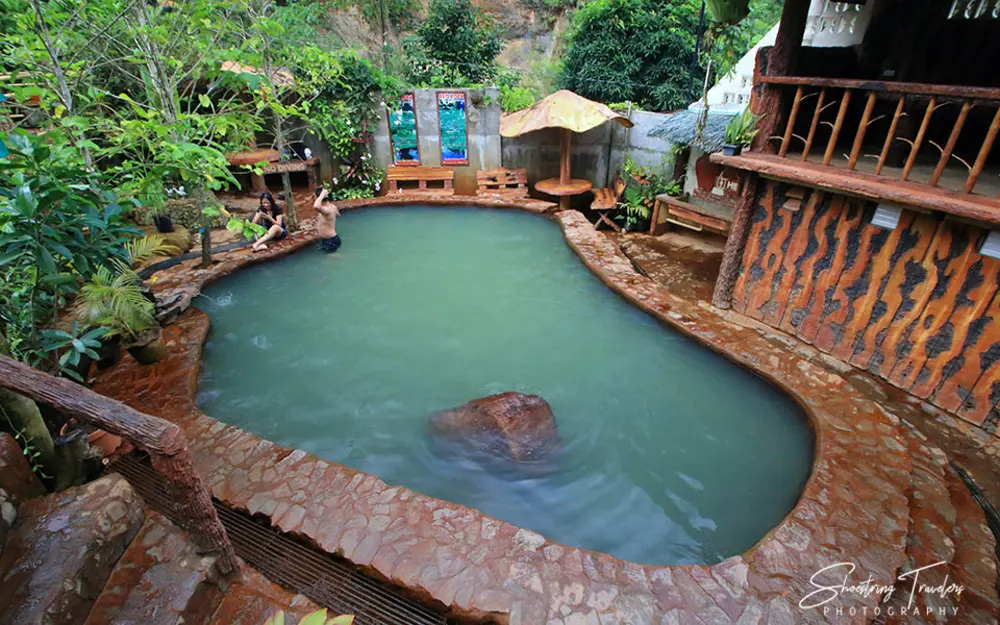 Mineral pool surrounded by tropical greenery at Red Rock Hot Spring in Valencia