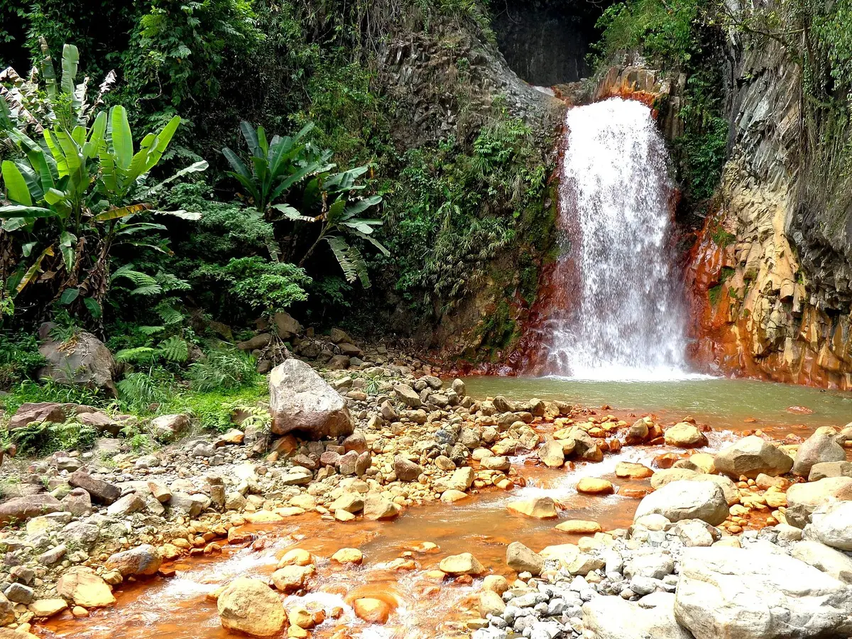 Reddish rocks and flowing water at Pulangbato Falls